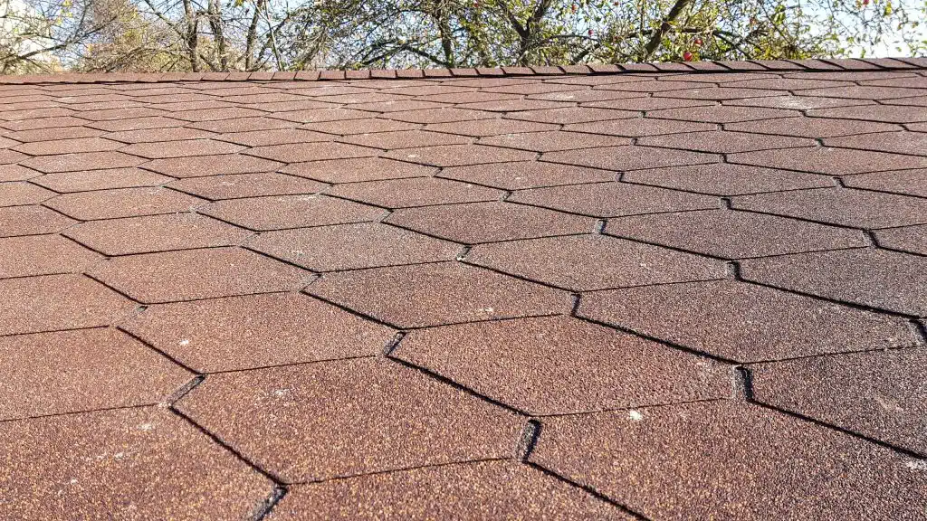 Hnědočervený střešní šindel s hexagonálním vzorem na střeše dřevěného zahradního domku.