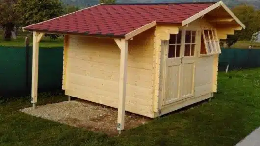 Malý dřevěný zahradní domek s červenou střechou.