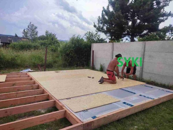 Zateplení dřevěného roštu zahradní chatky, detailní pohled na vrstvy izolace a dřevěnou konstrukci.